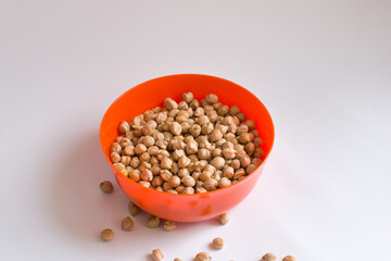 Uncooked chickpeas in an orange ball oblique view in isolated white background