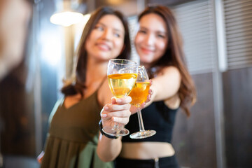 Focus on glass  of wine. two woman toasting drink to camera. young people lifestyle on holiday.