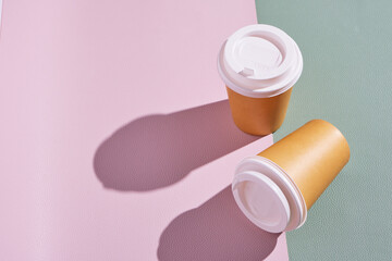 Two paper disposable cups for hot coffee and tea on pink green background .Concept and trend of takeaway food.