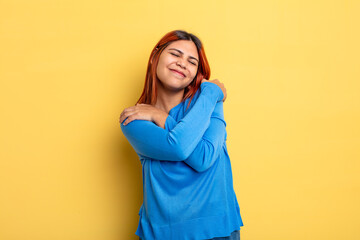 young hispanic woman feeling in love, smiling, cuddling and hugging self, staying single, being...