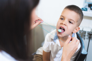 Woman speech therapist helps a boy correct the violation of his speech