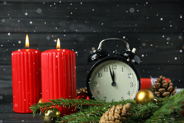 Fototapeta na wymiar Snow falling on table with burning candles, alarm clock and festive decor. Christmas eve