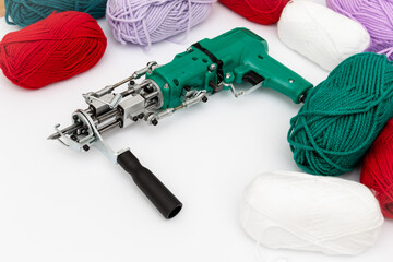 Tufting gun and skeins of yarn of various colors on white background. Cut and pile gun. Carpet hand...