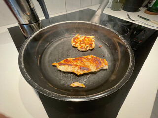 Cooking chicken breast on a kitchen pan