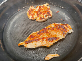 Cooking chicken breast on a kitchen pan