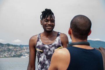 Black african athlete and her friend talking in the park on sunny day, in the background beautiful landscape.