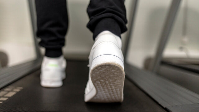 Fitness, workout and and healthy lifestyle concept. Male muscular feet in sneakers running on the treadmill at gym. Close-up image of fit man running on treadmill in gym, focus on sneaker sole.