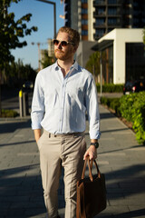 Young stylish businessman with e-scooter. Portrait of handsome man outdoors..