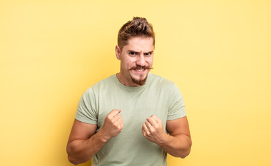 young handsome man shouting aggressively with annoyed, frustrated, angry look and tight fists,...