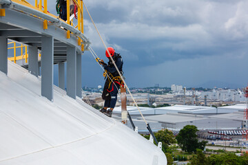 Male workers control rope down top roof tank rope access inspection of thickness shell plate...