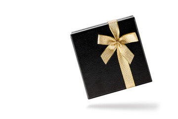 Black gift box with golden ribbon flying isolated on white background.