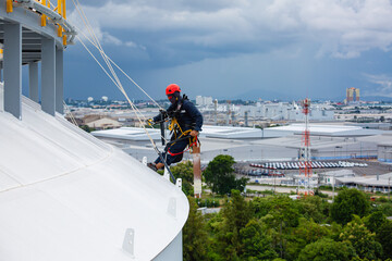 Male workers control rope down top roof tank rope access inspection of thickness shell plate storage tank gas