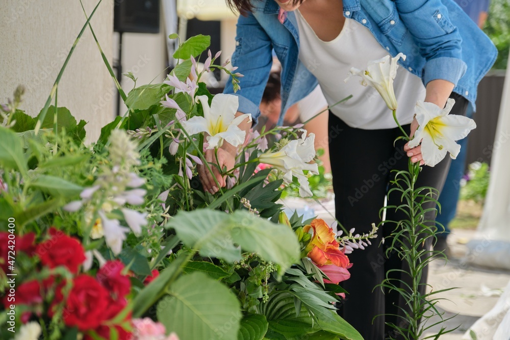 Wall mural Female florist doing floral arrangement outdoors. Flower basket creation workflow