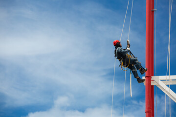 Male workers control swing rope down height tank rope access inspection of thickness pipeline and tank gas.