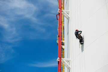 Male workers control swing rope down height tank rope access inspection of thickness pipeline and tank gas.
