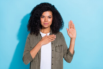 Photo of young african woman arm on chest sincere solemn promise tell the truth isolated over blue...