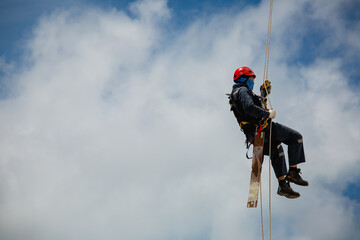 Male workers control swing rope down height tank rope access inspection of thickness tank gas background blue sky.