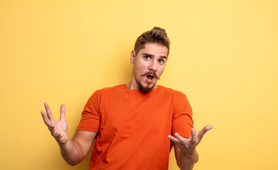 young handsome man open-mouthed and amazed, shocked and astonished with an unbelievable surprise....