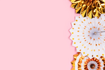Frame made of gold colored  paper fans on a pink background. Festive concept with place for text.