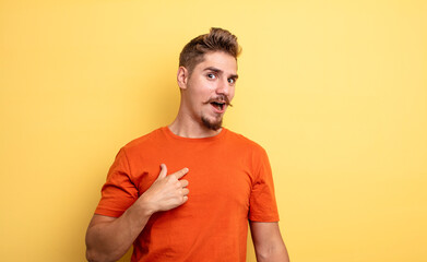 young handsome man looking shocked and surprised with mouth wide open, pointing to self. strange...