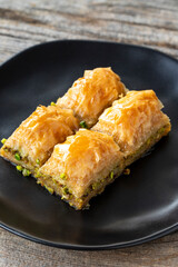 Pistachio baklava on a wooden background. Turkish style pistachio baklava presentation and service. Vertical view. close up
