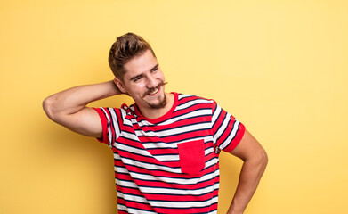 young handsome man smiling cheerfully and casually, taking hand to head with a positive, happy and...