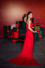 beautiful young woman in an elegant red dress with a gift box in her hands