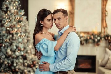 Fototapeta premium happy couple husband and wife at home in living room near christmas tree