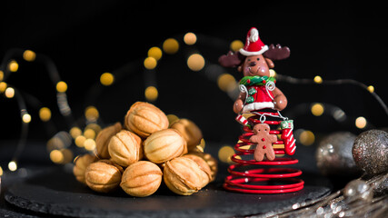 Cookies nuts with condensed milk against the background of New Year's garlands. New Year's sweets on a dark background. Homemade pastries. Toy New Year's deer.