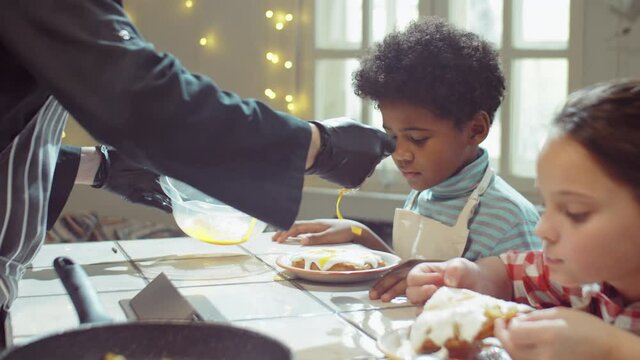 Little girl eating delicious waffle with sweet topping and enjoying its taste during culinary masterclass