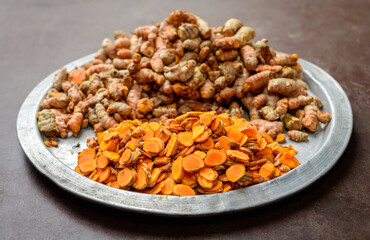 Turmeric (Curcuma longa) close up, fresh sliced turmeric and roots pile on a plate.