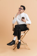 Young middle eastern man using cellphone while sitting on chair