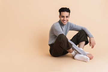 Young middle eastern man smiling while sitting on floor