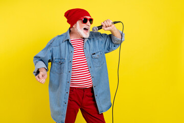 Portrait of attractive cheerful funky grey-haired man singing hit single isolated over bright...