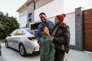Black family smiling and talking together while standing on parking