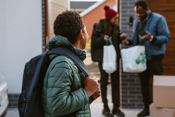 Obraz premium Black boy standing on parking during moving with his family