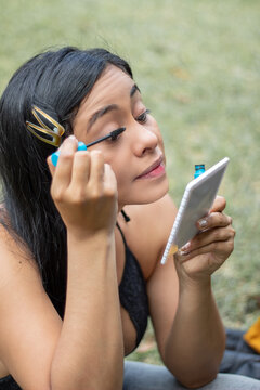 Girl Putting On Makeup In The Park