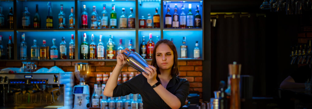 young attractive woman bartender Making Cocktail Using Shaker in bar