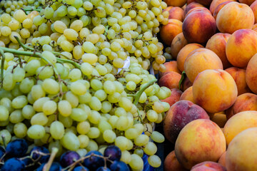 White ripe fresh grapes on a shop counter near blue grapes, peaches