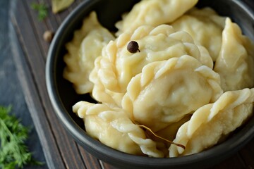 Dumplings (vareniki, pierogi, pyrohy) with potatoes, herbs, spices and butterin a ceramic bowl on a...
