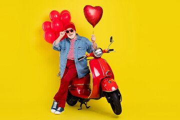 Portrait of elderly retired pensioner trendy cheery man sitting on moped hold heart isolated over vivid yellow color background