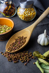 cardamon clay pot, sichuan paper in wood spoon, chilli paper and juniper berry, garlic, kaffir lime and corn in jar
