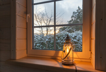 Festive lantern on a wooden window sill in winter indoors.