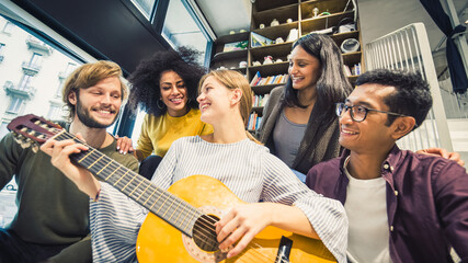 Group of five multiracial young people in casual clothes singing and playng music indoor, young friends having fun and spending time together, millennials lifestyle