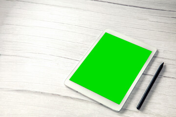 Digital tablet computer with pen and isolated green screen white wooden desk top view, copy space for film,movie, moving image