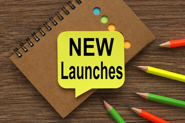 NEW LAUNCHES. text on yellow sticker. on wood background