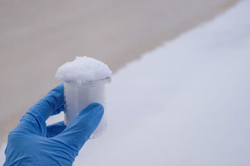 Hand in blue glove holding snow sample from the sea, water diversion, ecology concept. Copy space