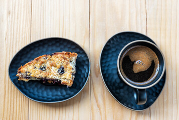 Homemade delicious sliced Apple Blueberry Pie on a black serving plate and a cup of black coffee on a wooden table. Top View