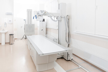 X-ray department in modern hospital. Radiology room with scan machine with empty bed. Technician adjusting an x-ray machine. Scanning chest, heart, lungs in modern clinic office