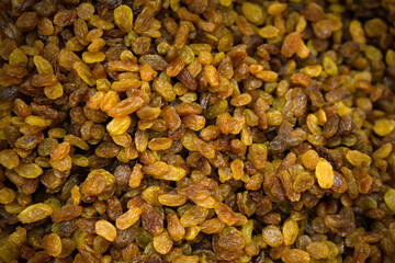 man picks up loose dried raisins with a shovel